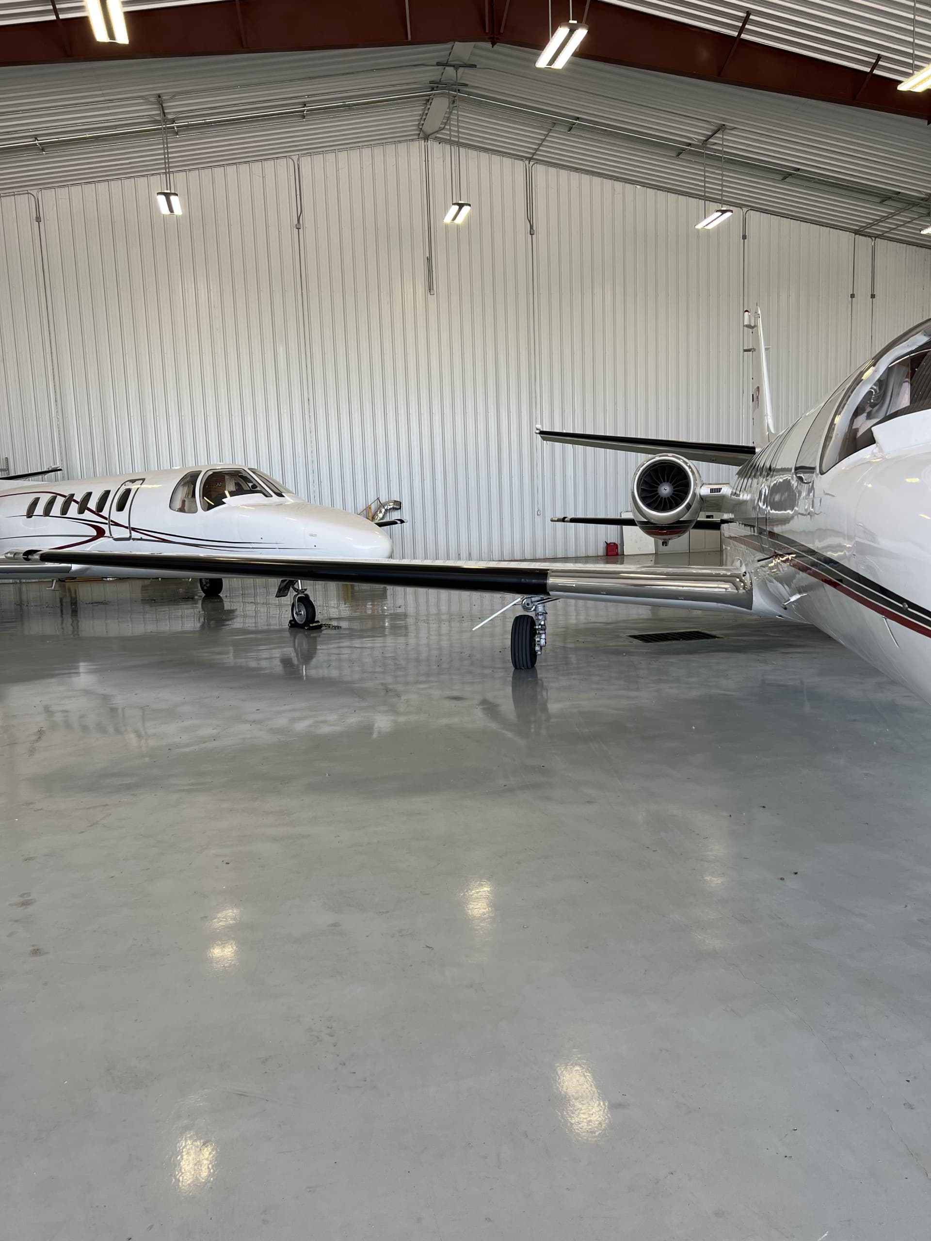 Two business jets parked inside the Superior Aviation hangar, reflected on the polished floor